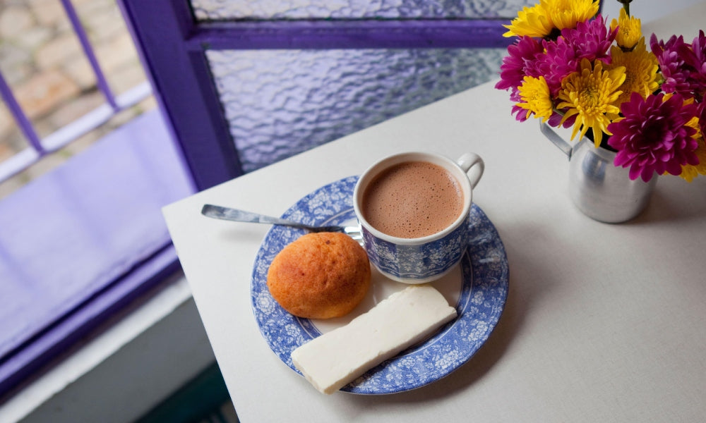 A cup of hot chocolate with a piece of cheese on the saucer