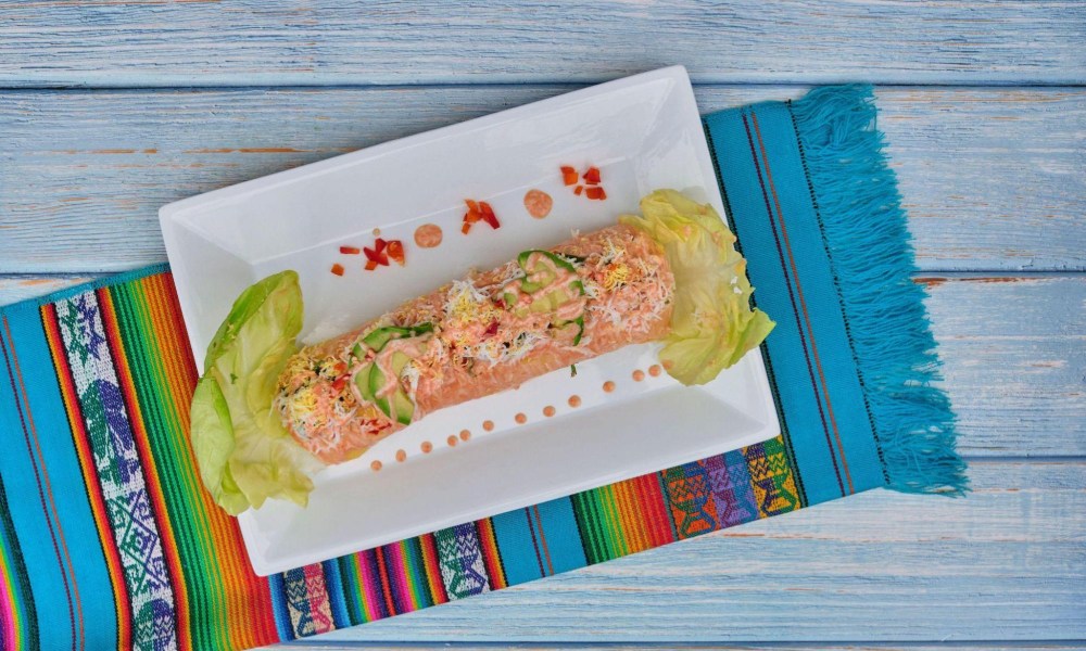 colorful causa limeña or peruvian causa on a white plate, on top of a vibrant, latin-inspired placemat