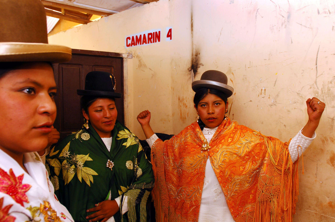 three luchadoras 'cholas' in traditional indigenous outfits and traditional bowler hats