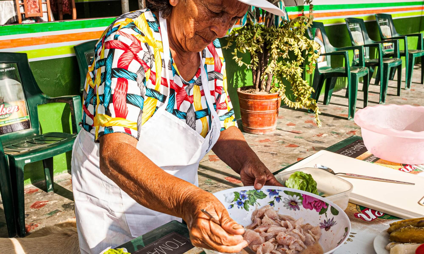 An older Peruvian lady prepares ceviche outdoors