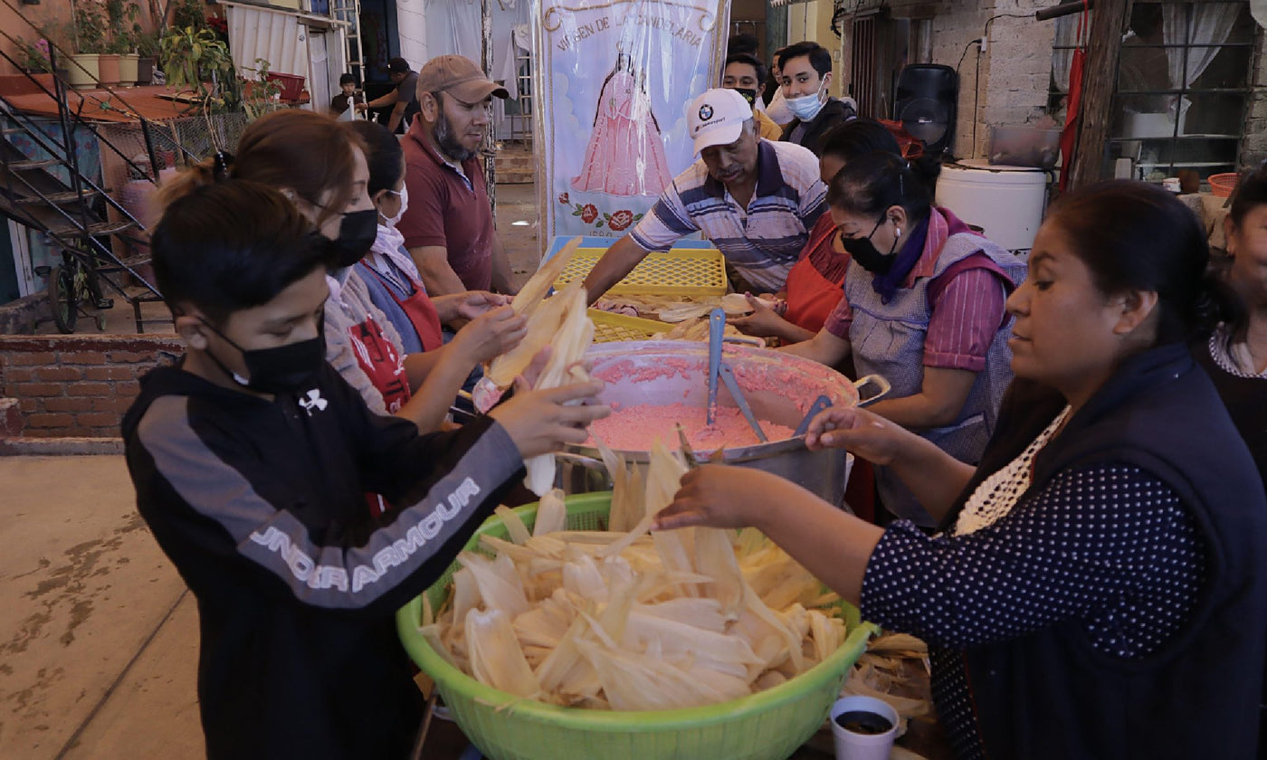 Women stand around a table as they make tamales