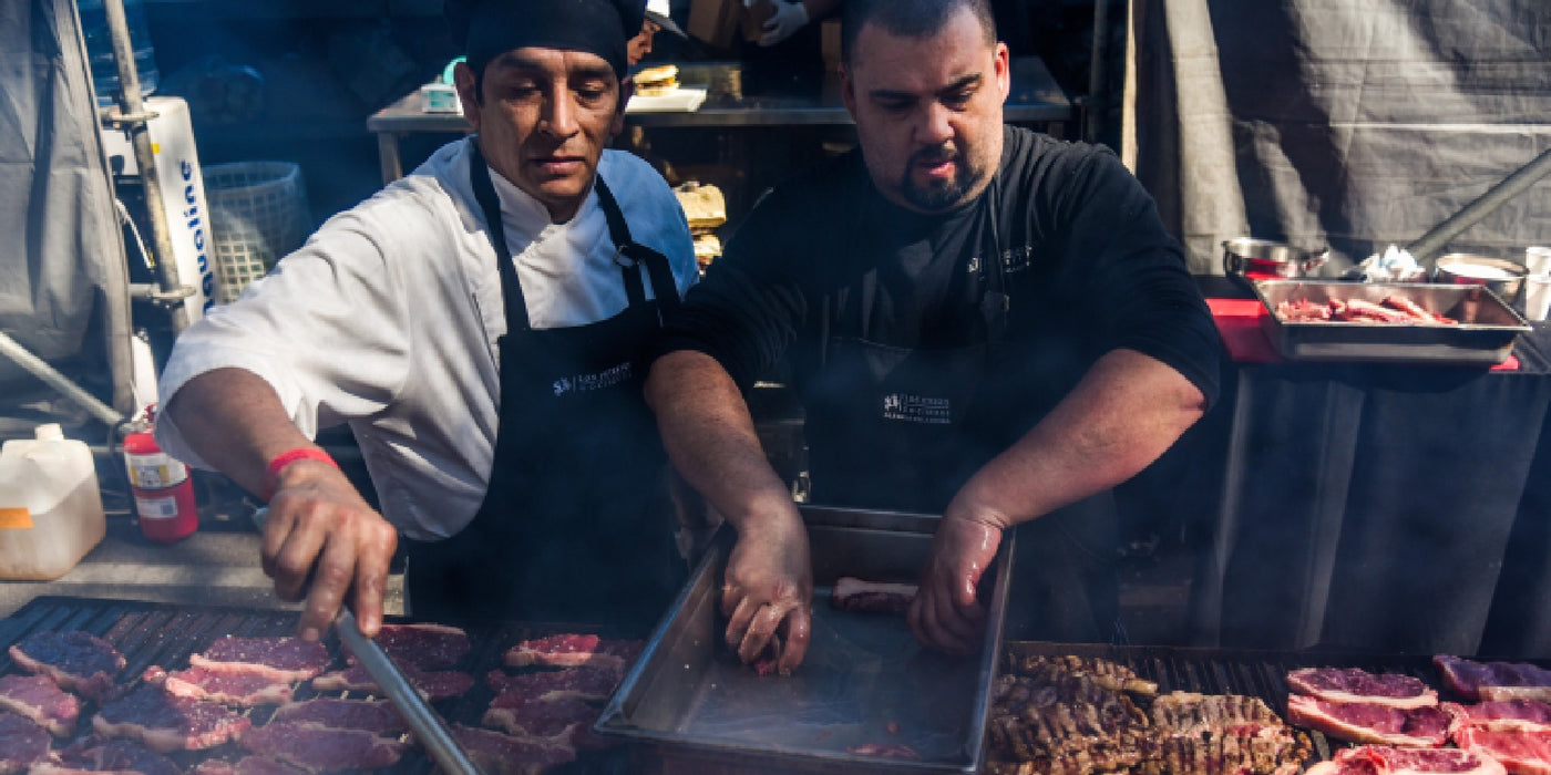 Diego Biondi and another chef managing a huge asado
