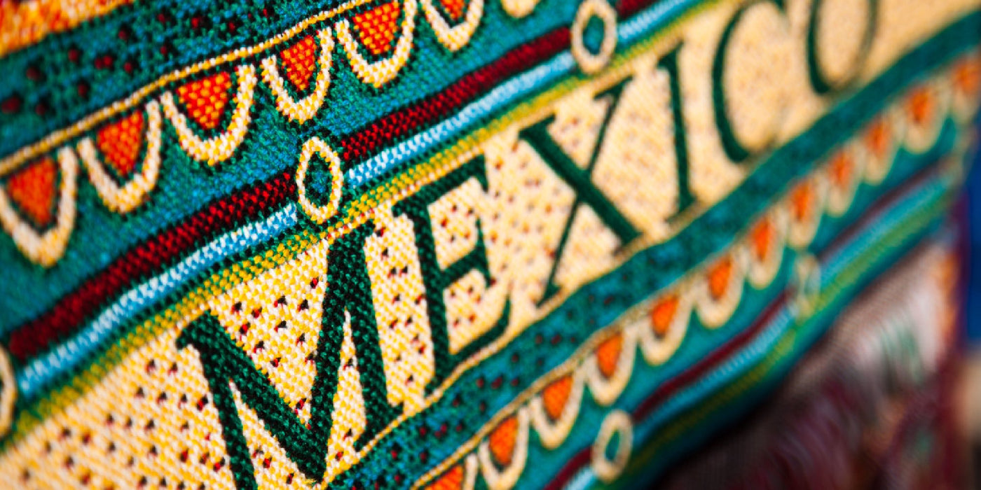 Intricate Central American indigenous-style tapestry which spells "Mexico" in bright colors