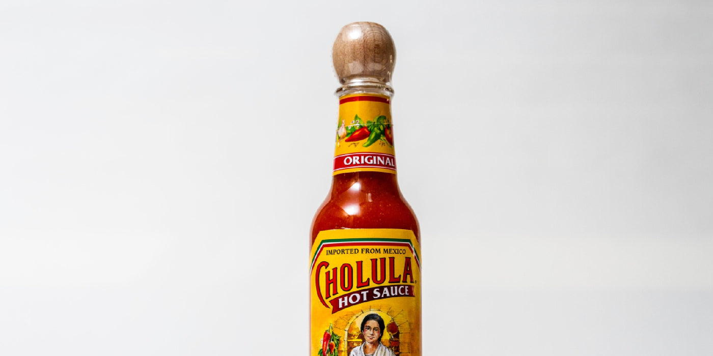 A bottle of Cholula Hot Sauce against a plain backdrop
