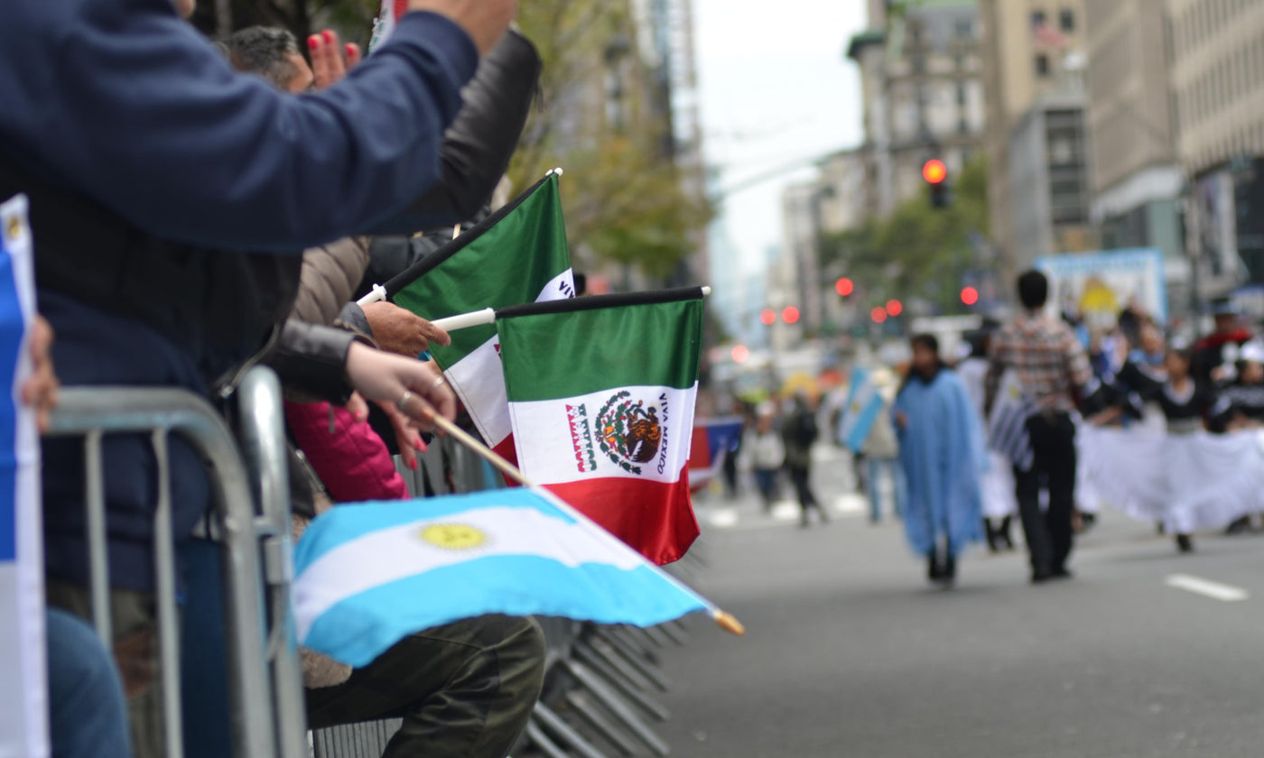 People waving the flags of Argentina and Mexico as a procession goes by for Hispanic Heritage Month