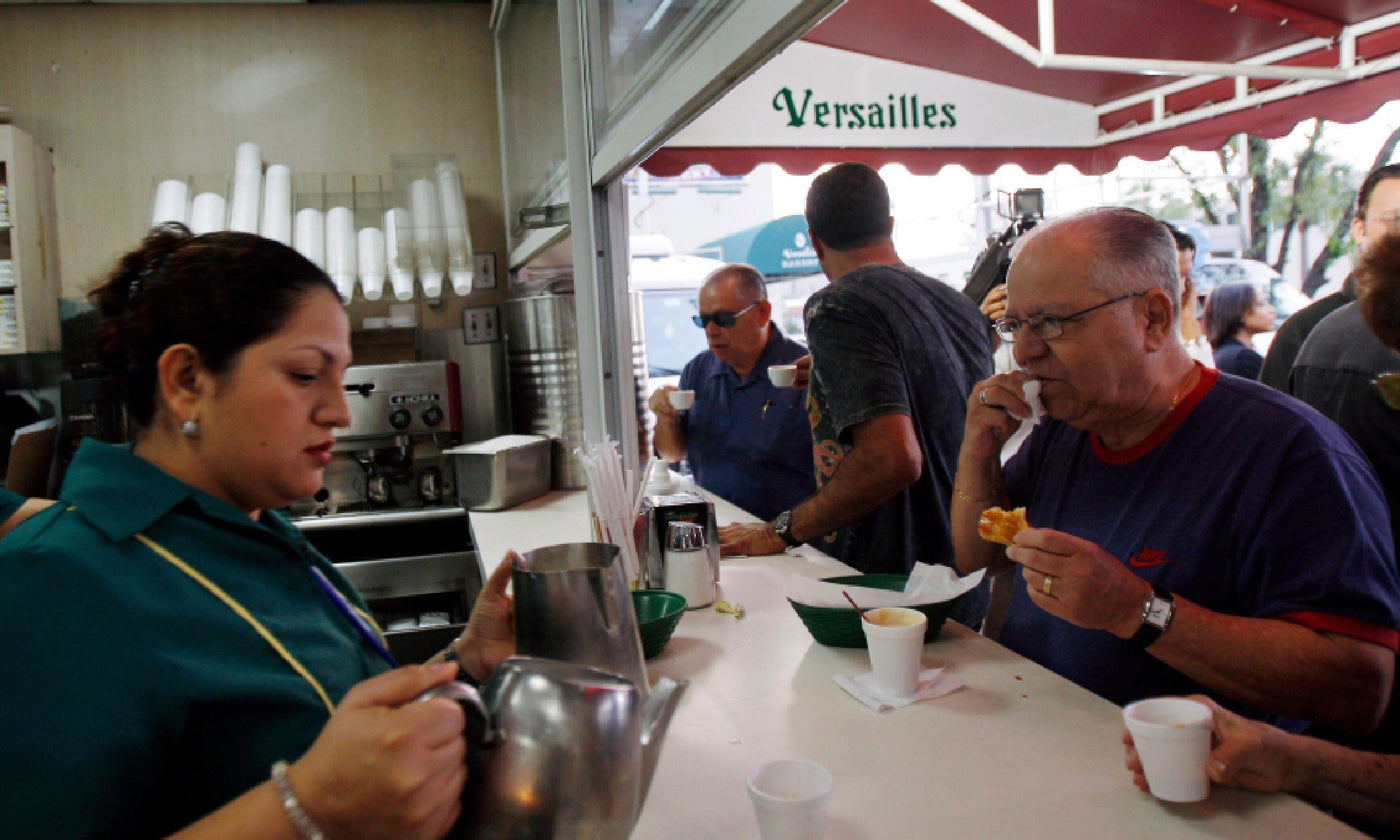 Cuban woman serves coffee to a man stood at a ventanita in Miami
