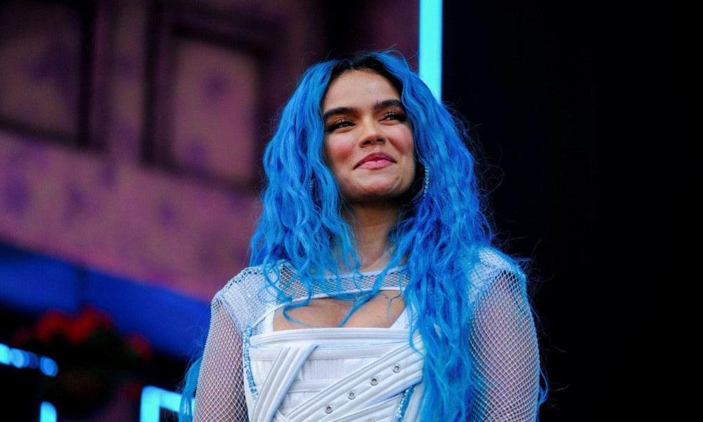 Karol G with blue hair smiling on stage