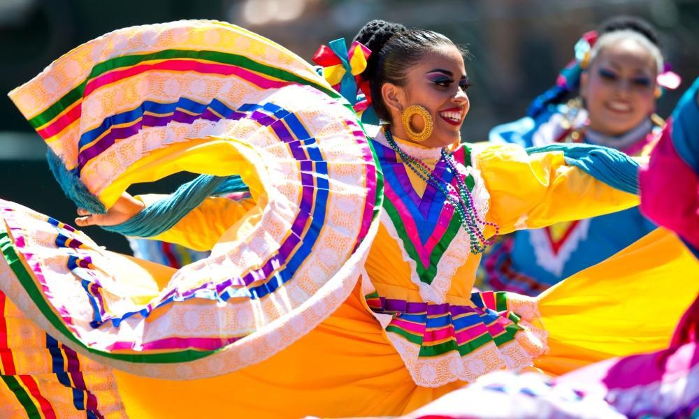 Woman dances in colorful traditional costume for Hispanic Heritage parade