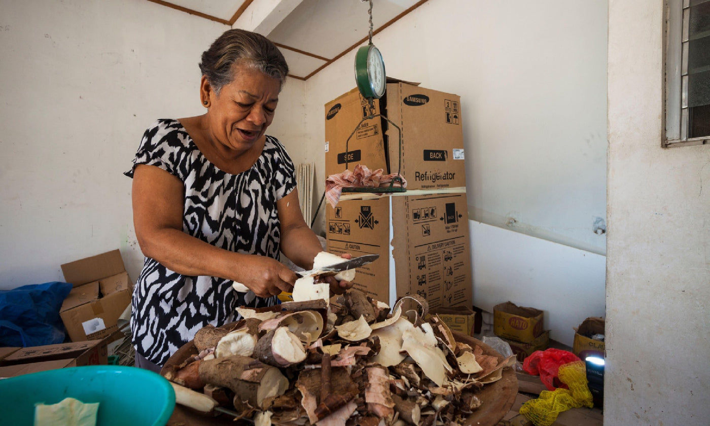A woman peeling a giant pile of yuca tubers