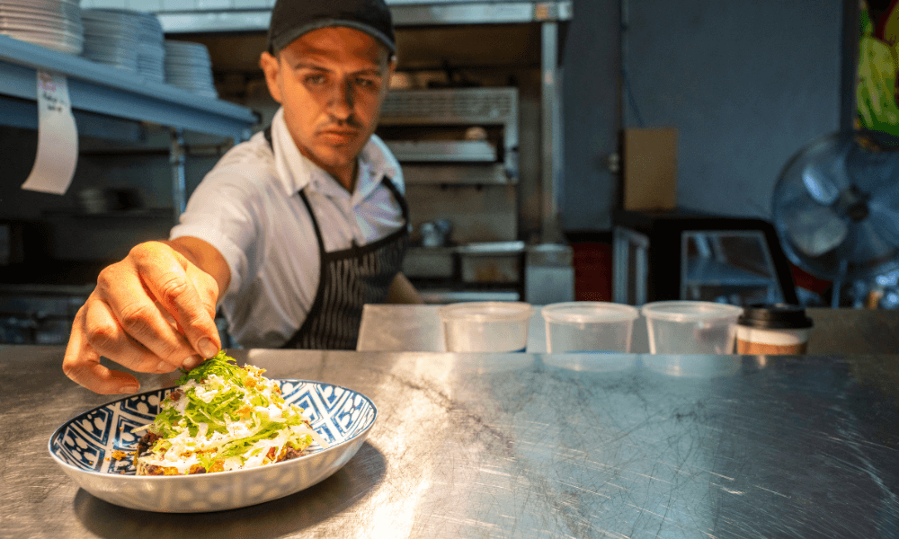 Chef adding finishing touches to Mexican food at a restaurant pass