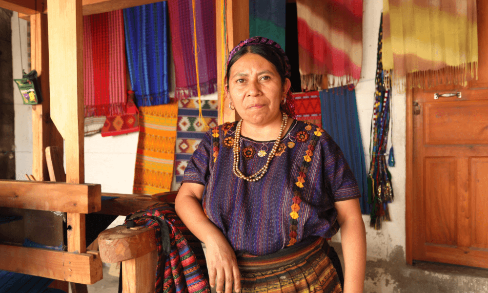 Tejedora Maya standing in front of her beautiful tapesteries