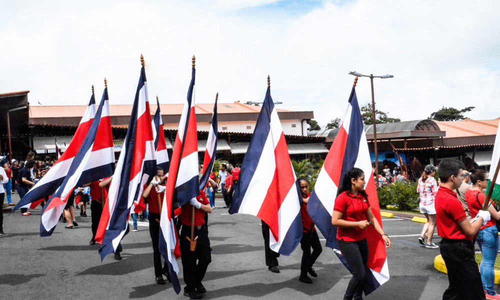 People parade through the streets waving large flags of Costa Rica