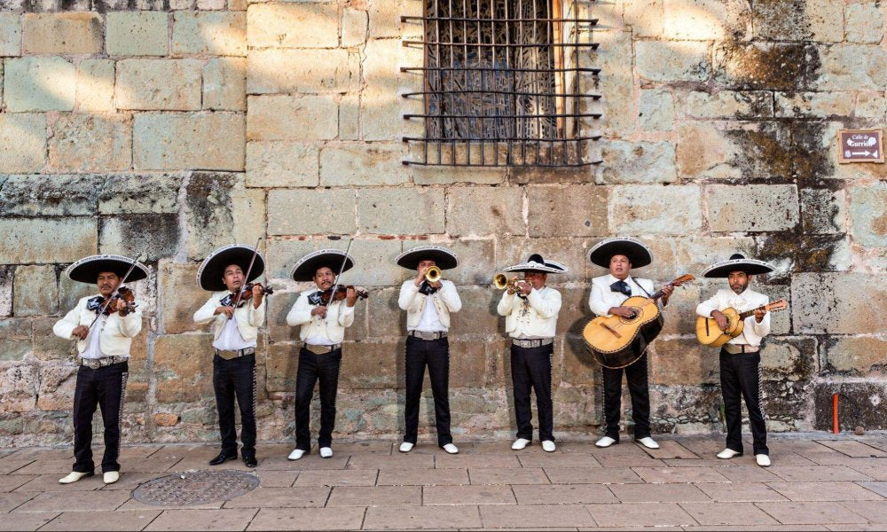 7 young boys dressed in mariachi clothes and playing outside an old building in Mexico